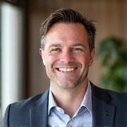 Portrait of Marcus Thorne, a compassionate and approachable man with short dark hair and a confident smile. He is wearing a professional yet relaxed blazer.